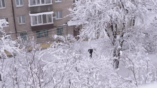 Een man wist weg van sneeuw in Yard van een oud woongebouw — Stockvideo