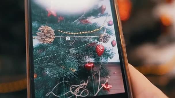 Weibliche Hände fotografieren den Weihnachtsbaum auf einem Smartphone. 4K. Nahaufnahme — Stockvideo