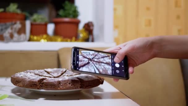 Des femmes prennent une photo d'une tarte au chocolat dans la cuisine sur un téléphone intelligent. 4K — Video