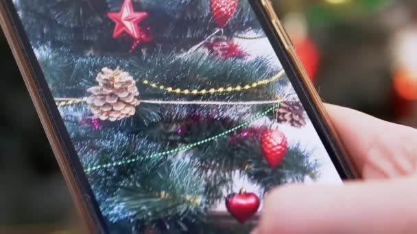女性的手正在智能手机上拍摄圣诞树的视频。靠近点 — 图库视频影像
