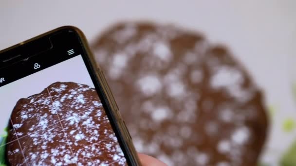 女性の手はスマートフォンのキッチンでチョコレートパイのビデオを撮影します。4K — ストック動画