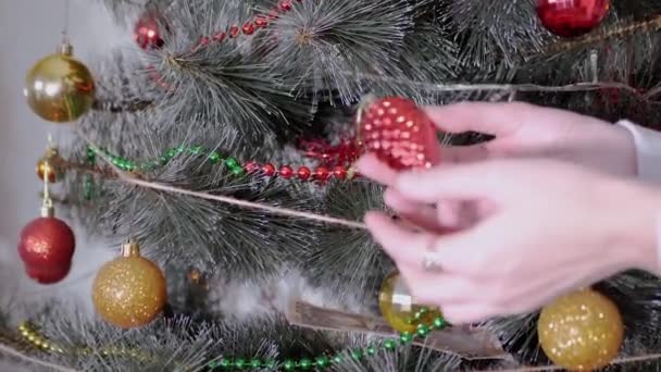 Las manos femeninas decoran el árbol de Navidad con decoraciones navideñas de año nuevo. Zoom: — Vídeos de Stock