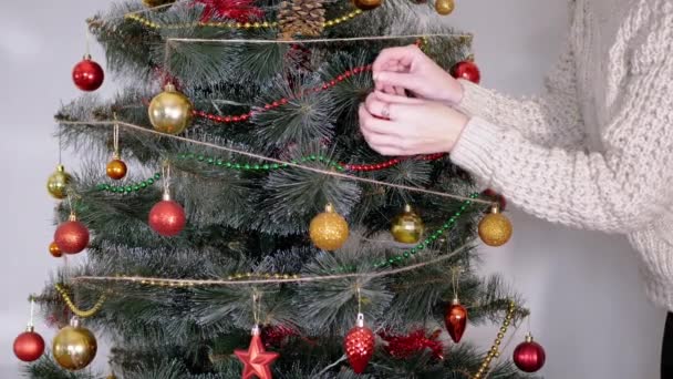 Le mani femminili decorano l'albero di Natale con decorazioni natalizie di Capodanno. 4K — Video Stock