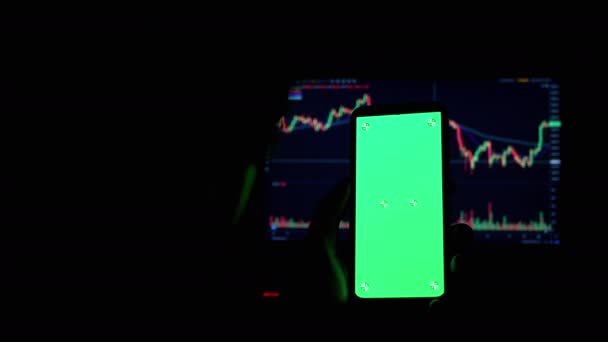 一个商人在一间黑暗的房间里手里拿着一个绿色屏幕的智能手机。4K — 图库视频影像