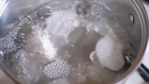 Två ägg kokar i en gryta med kokande vatten. Långsamma rörelser. Närbild — Stockvideo