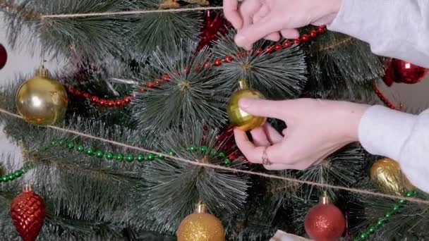 Las manos femeninas decoran el árbol de Navidad con decoraciones navideñas de año nuevo. Zoom: — Vídeos de Stock