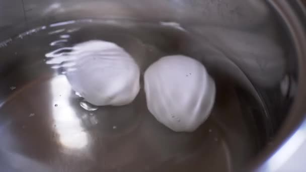 Zwei Eier kochen in einem Topf mit kochendem Wasser. Zeitlupe. Nahaufnahme — Stockvideo