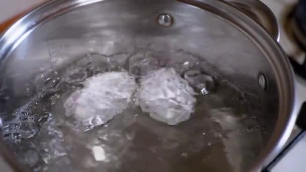 Zwei Eier kochen in einem Topf mit kochendem Wasser. Zeitlupe. Nahaufnahme — Stockvideo