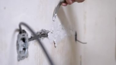 Elektrik kablolarını döşedikten sonra beton duvardaki çatlakları macunla kapatan kurucu