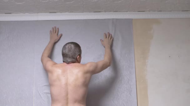 Samec lepí šedý papír tapety na zdi pod stropem. Zadní pohled. 4K — Stock video