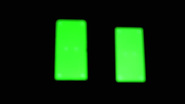 Zwart silhouet van een Hand dia 's door groen scherm van een smartphone in een donkere kamer — Stockvideo