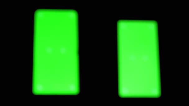 Silhouette noire d'une main glisse par écran vert d'un smartphone dans une pièce sombre — Video