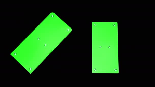 緑の画面を持つ2つのスマートフォン,クロマキー,黒の背景にマーカー.4K — ストック動画