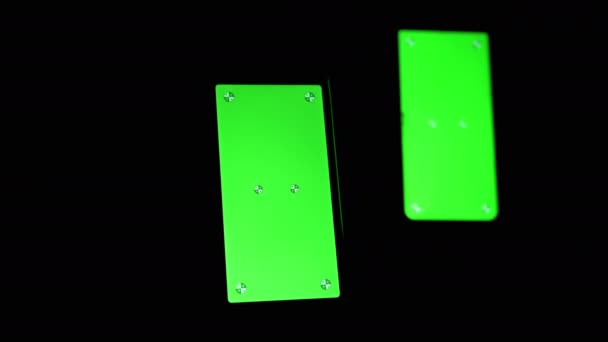 Dos teléfonos inteligentes con una pantalla verde, clave de croma, marcadores en un fondo negro — Vídeo de stock