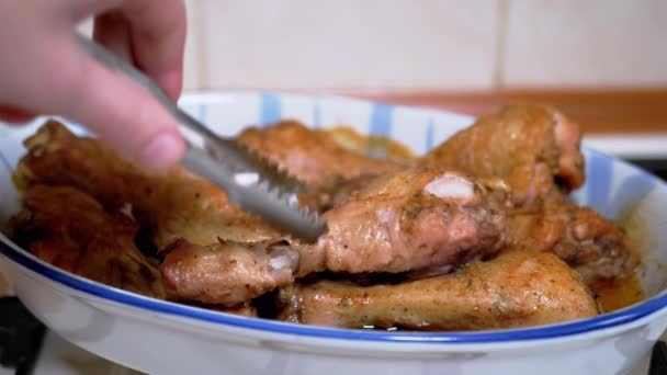 Kobieta układa gotowane pieczone nóżki kurczaka z formy odpornej na ciepło z kleszczami — Wideo stockowe