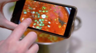 Bir kadın, Ukrayna 'nın geleneksel kırmızı borsasının fotoğrafına akıllı telefondan bakıyor.