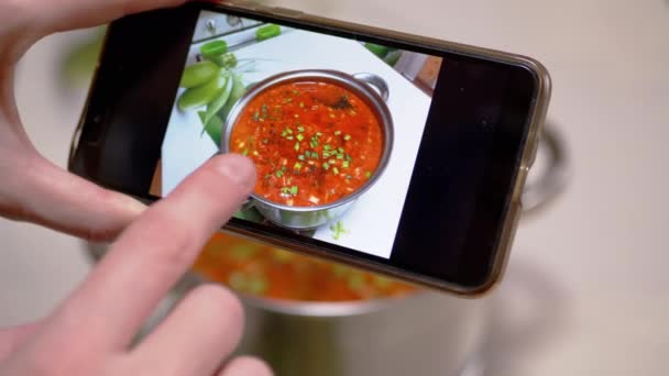 A Woman Looks at a Photo of Traditional Ukrainian Red Borscht on a Smartphone — Stok Video
