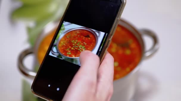 Een vrouw kijkt naar een foto van traditionele Oekraïense rode Borscht in een smartphone — Stockvideo