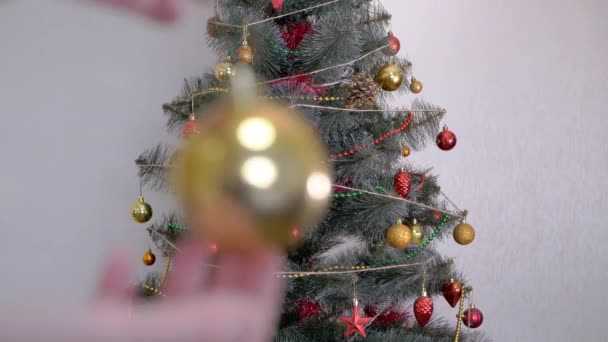 Las manos femeninas decoran el árbol de Navidad con decoraciones navideñas de año nuevo. 4K — Vídeos de Stock