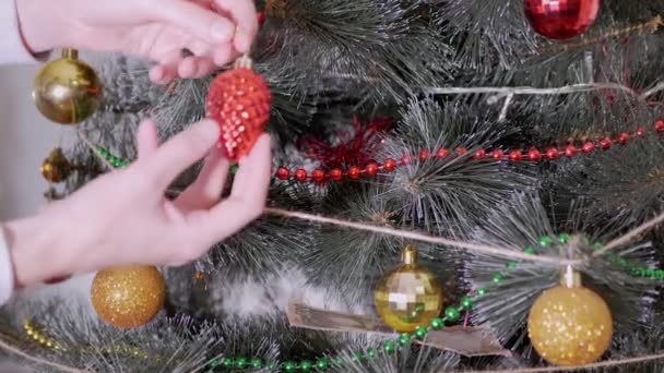 Жіночі руки прикрашають різдвяну ялинку новорічними прикрасами. Збільшити — стокове відео