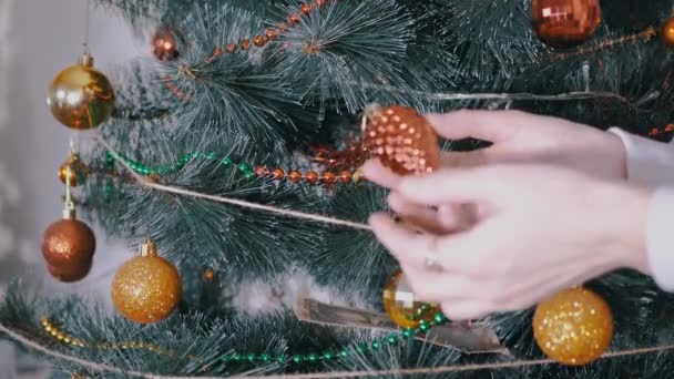 Las manos femeninas decoran el árbol de Navidad con decoraciones navideñas de año nuevo. 4K — Vídeo de stock