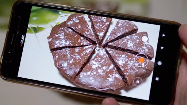 Female Hands Shoots Видео шоколадного пирога на кухне на смартфоне. 4K — стоковое видео