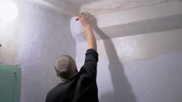 Mannelijke verft de gevel van de muur in de ingang met een penseel met witte verf — Stockvideo