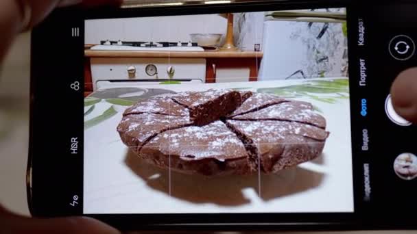 Kvinnliga händer Ta en bild av en chokladpaj i köket på en smart telefon. 4K — Stockvideo
