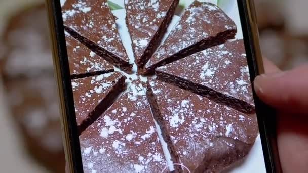 Weibliche Hände filmen mit einem Smartphone einen Schokoladenkuchen in der Küche. Zoom — Stockvideo