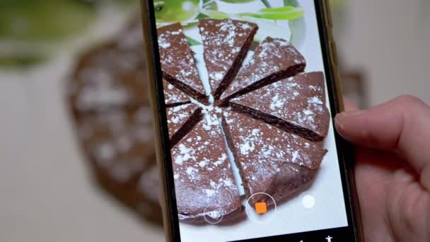 As mãos femininas filmam vídeo de uma torta de chocolate na cozinha em um telefone inteligente. 4K — Vídeo de Stock