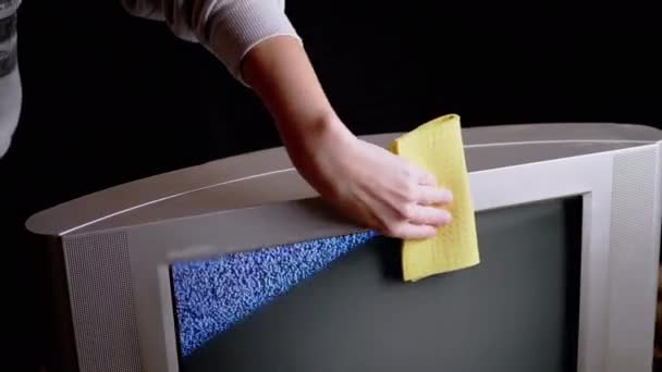 Female Hand Wipes Dust with a Yellow Rag from Surface of an Old TV in Dark Room — Stock Video