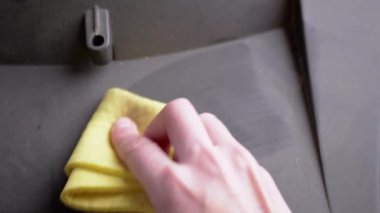 Eski bir televizyonun yüzeyinden sarı bir paçavrayla kadın el temizleme tozu. 4K