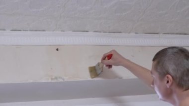 Erkek, Duvar Kağıdı Fırçası ile Duvara Yapıştırıcı Uyduruyor. 4 bin. Kapat.