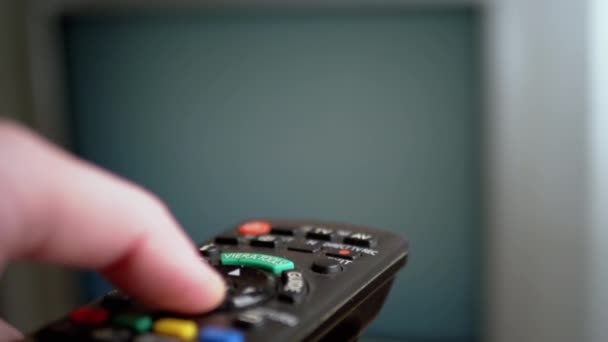 A Male Hand Holds a Remote Controller and Switches Flickering Channels on Screen — Stock Video