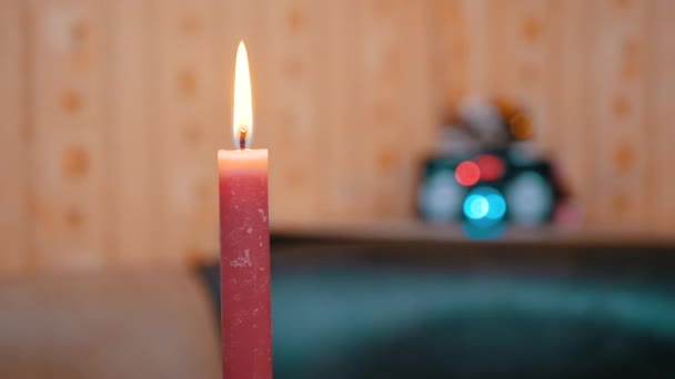 Candela rossa ardente con una fiamma in movimento brillante su uno sfondo sfocato di luci — Video Stock