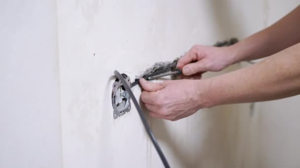 Male Electrician está colocando un cable aislante en la pared para instalar un zócalo. 4K — Vídeo de stock