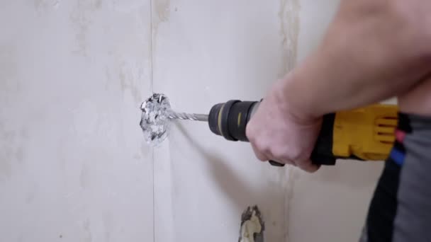 Budowniczy za pomocą wykrawacza robi dziurę w betonowym murze, aby zainstalować gniazdko. — Wideo stockowe