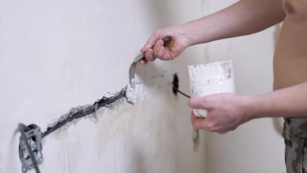 Bauarbeiter mit Spachtelmasse schließt Risse in Betonwand nach Verlegung von Elektroleitungen — Stockvideo