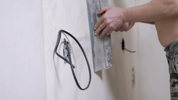 Bouwer met putty sluit scheuren in betonnen muur na het leggen van elektrische bedrading — Stockvideo