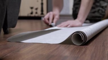 Erkek, Yerde Otururken, Bir Bıçakla Yapıştırmak için Duvar Kağıdı Şeridini keser