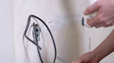 Elektrik kablolarını döşedikten sonra beton duvardaki çatlakları macunla kapatan kurucu