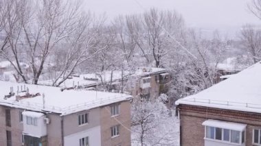 Eski Konut binalarının avlusundaki ağaçların tepelerinden kar yağıyor.
