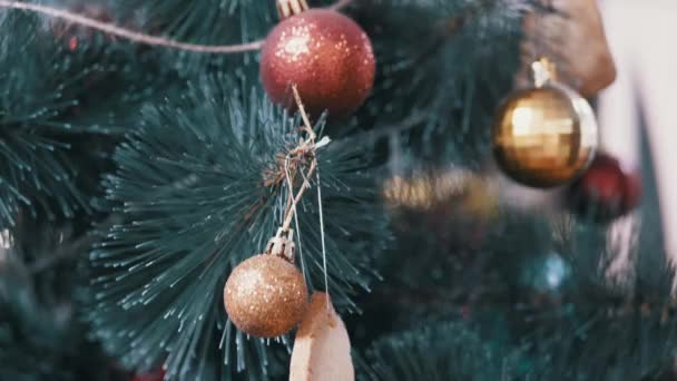 Árbol de Navidad decorado con bolas de vidrio amarillo, rojo, pan de jengibre en las ramas. — Vídeos de Stock