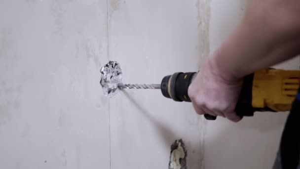 Ένας κατασκευαστής χρησιμοποιώντας ένα Puncher κάνει μια τρύπα σε ένα τσιμεντένιο τοίχο για να εγκαταστήσετε ένα Outlet. — Αρχείο Βίντεο