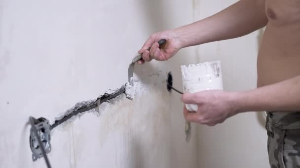 Constructeur avec mastic ferme les fissures dans le mur de béton après avoir posé le câblage électrique — Video