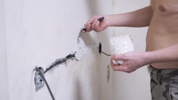 Stavitel s tmely uzavírá praskliny v betonové zdi po položení elektrické instalace — Stock video