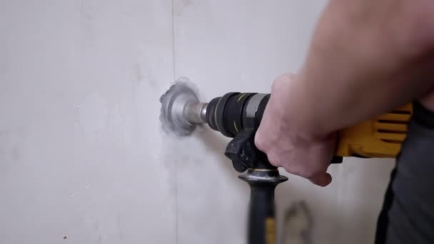 パンチャーを使用するビルダーは、電源ソケットを設定するためにコンクリートの壁に穴を開けます — ストック動画