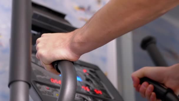 Atleta entrena en un entrenador elíptico en casa, viendo el ritmo cardíaco en el monitor — Vídeo de stock