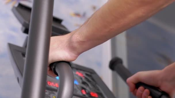 L'atleta si allena su un addestratore ellittico a casa, osservando la frequenza cardiaca sul monitor — Video Stock