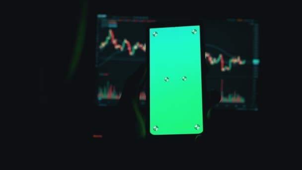 Handlowiec trzyma smartfon z zielonym ekranem w rękach w ciemnym pokoju. 4K — Wideo stockowe